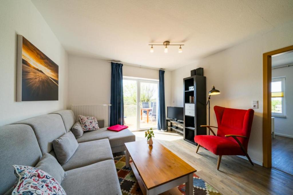 sala de estar con sofá y silla roja en Ferienwohnung Möwe, en Borkum