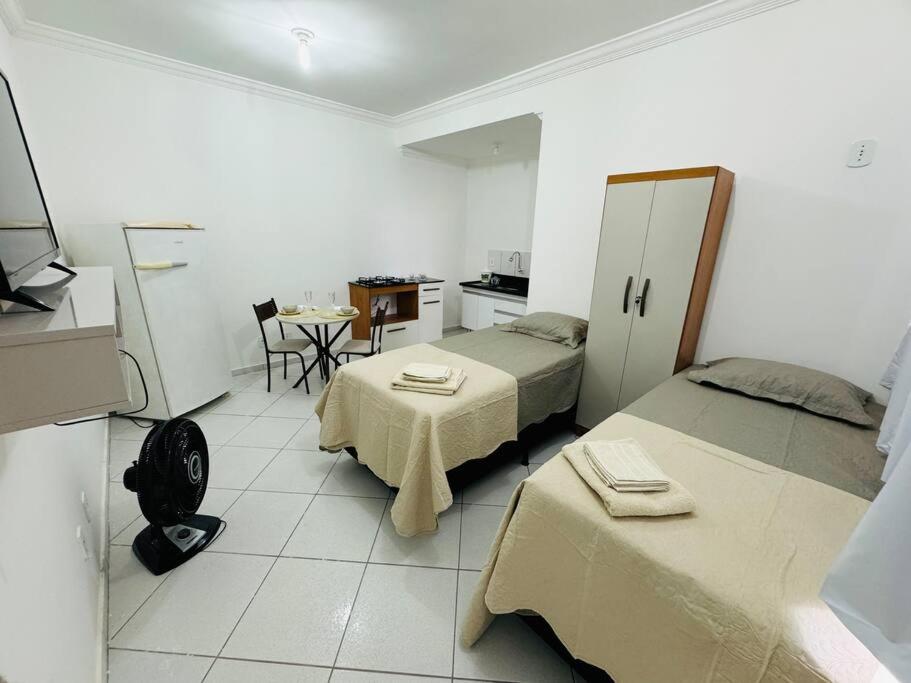 a room with two beds and a table and a kitchen at Kitnet cheia de estilo, ipatinga mg in Ipatinga