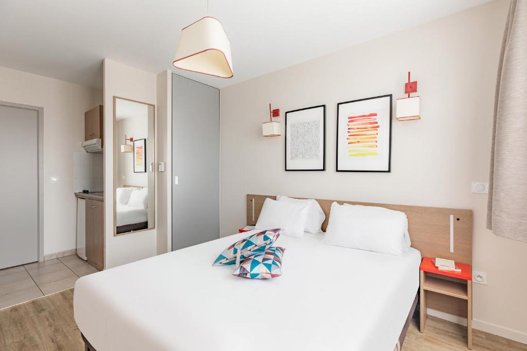 Un dormitorio con una gran cama blanca con almohadas blancas. en Appart&#39;City Confort Orléans, en Orléans