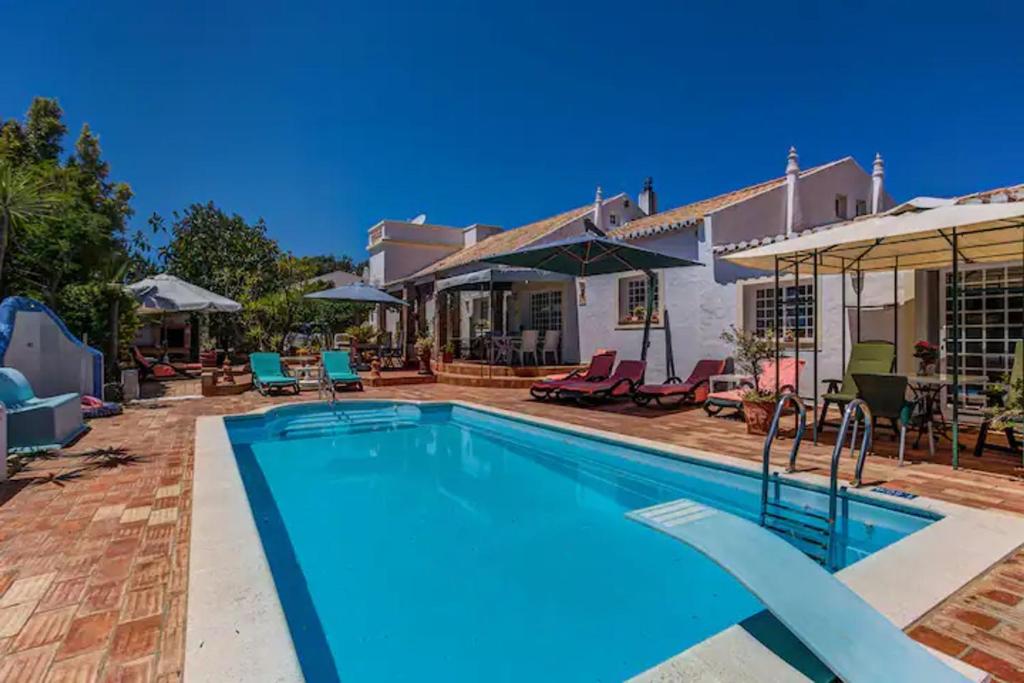 a swimming pool with chairs and a house at Quinta Velha Authentic Farmhouse Experience by LovelyStay in Senhora do Verde