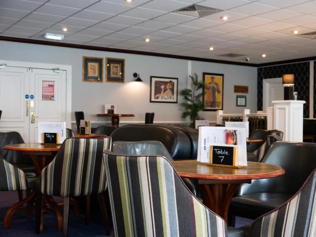 a waiting room with tables and chairs in a restaurant at Britannia Hotel Newcastle Airport in Newcastle upon Tyne