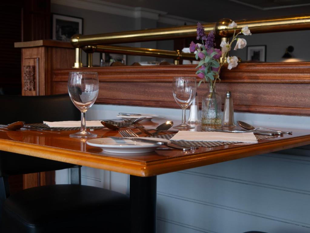 a table with two glasses and a vase of flowers at Britannia Hotel Newcastle Airport in Newcastle upon Tyne