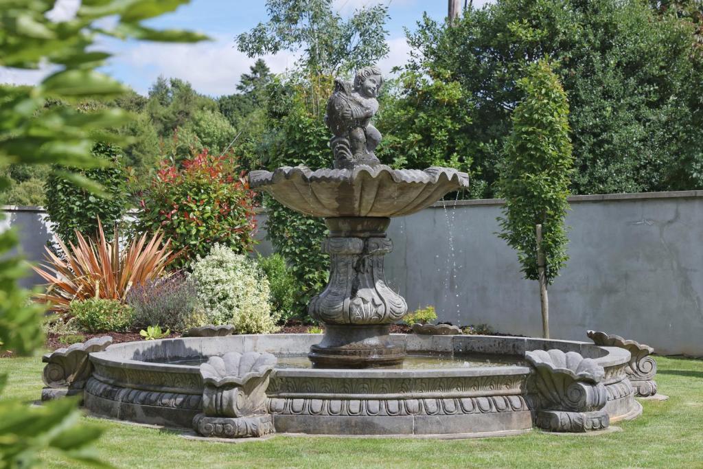 a stone fountain in a garden with a statue at Meadowside B&B in Bunclody