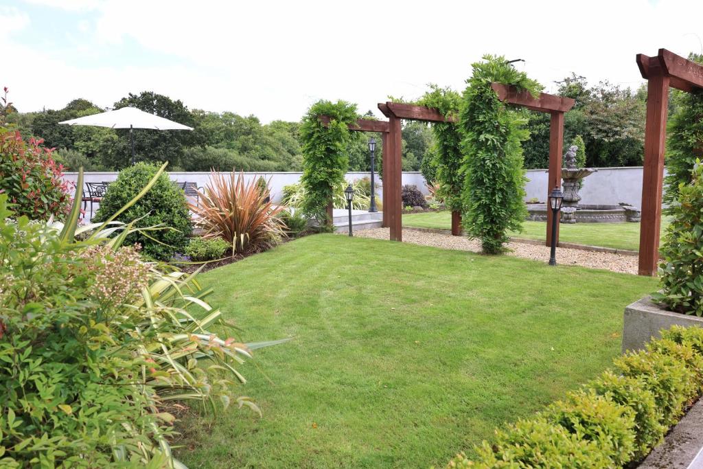a garden with an arbor and green grass at Meadowside B&B in Bunclody