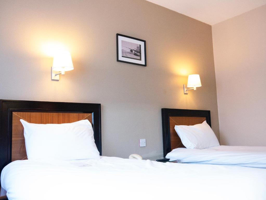 two beds in a hotel room with white pillows at Britannia Hotel Newcastle Airport in Newcastle upon Tyne