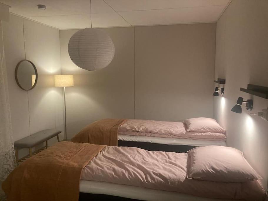 a room with two beds and a lamp and a mirror at Paritalon huoneisto in Raahe