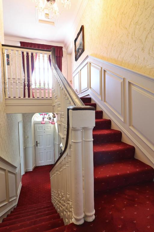 a staircase with red carpet and a white stair case at Meadowside B&B in Bunclody