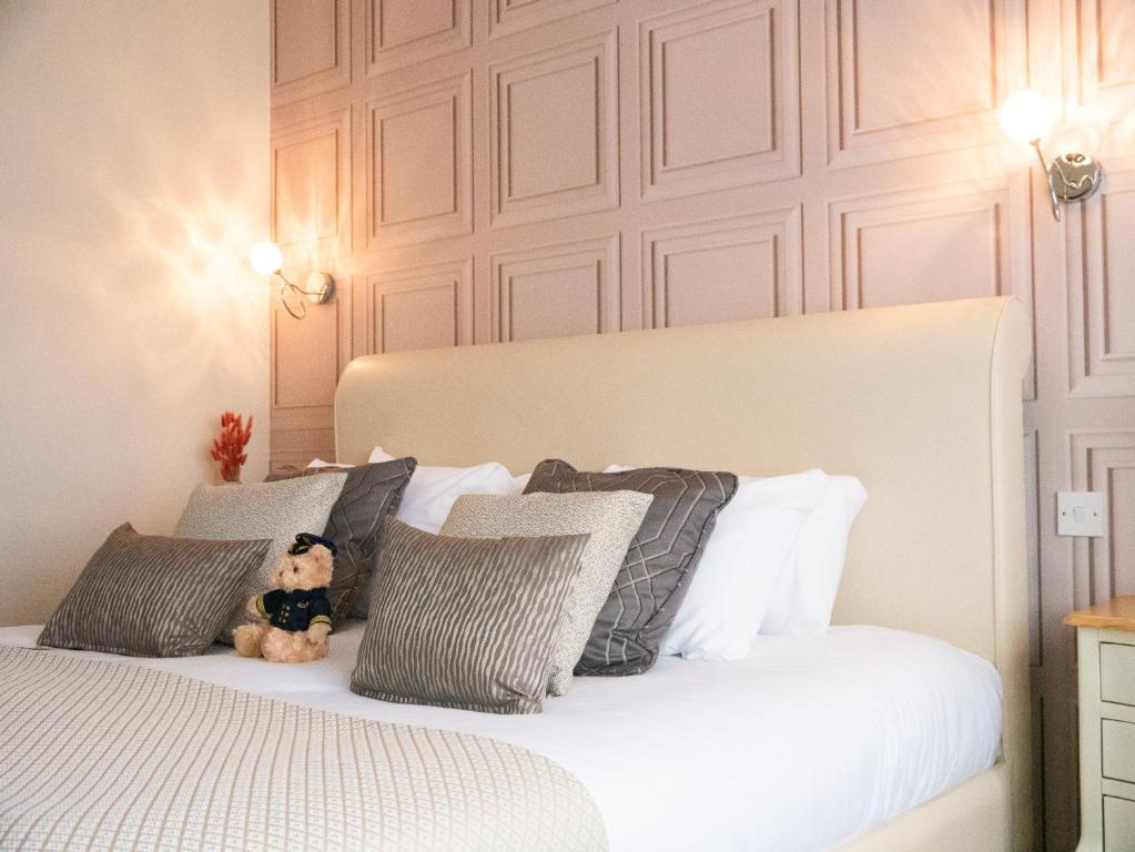 a teddy bear sitting on a bed with pillows at Britannia Hotel Newcastle Airport in Newcastle upon Tyne
