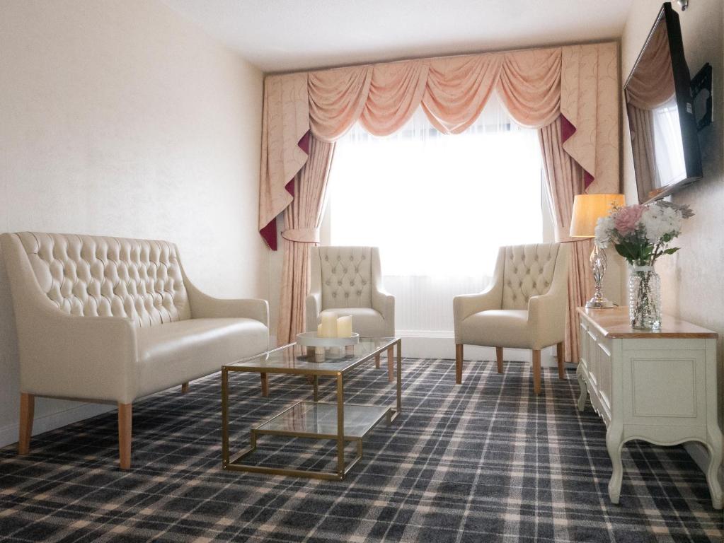 a waiting room with chairs and a table and a window at Britannia Hotel Newcastle Airport in Newcastle upon Tyne