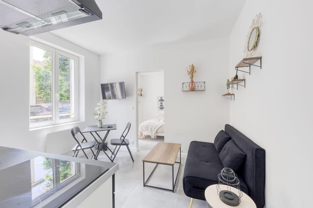 un salon avec un canapé noir et une table dans l'établissement Zen résidence, à Aubervilliers