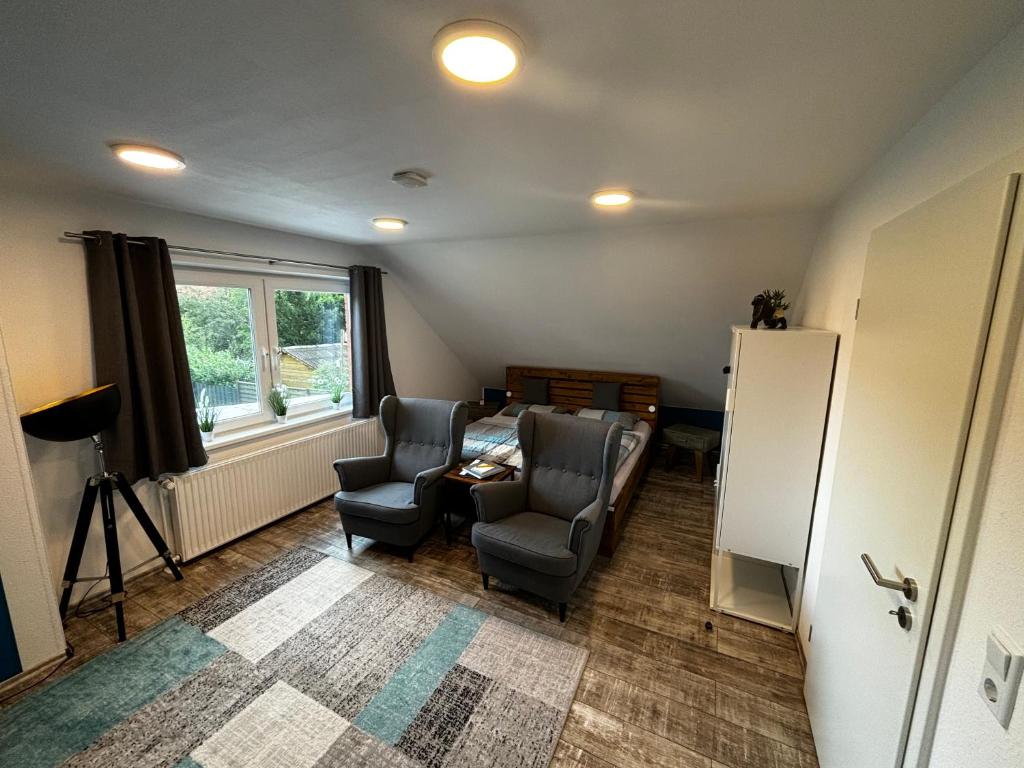 ein Wohnzimmer mit 2 Stühlen und einem Kühlschrank in der Unterkunft FEWO FloTi Ferienwohnung Augustfehn in Apen
