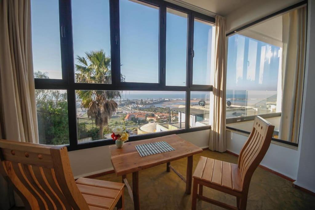 a room with a table and chairs and large windows at Appartement La Plage Vue sur Mer pour les familles in Oualidia