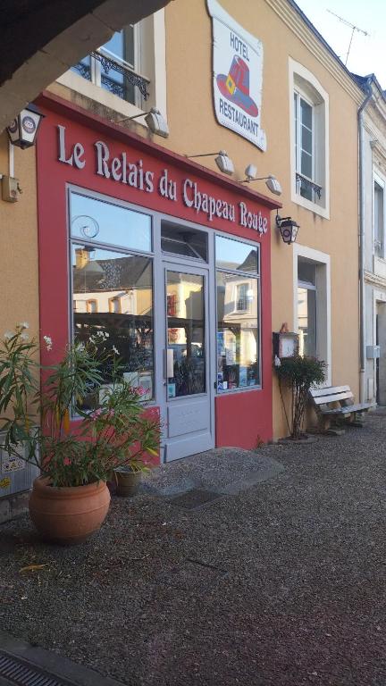un magasin avec une enseigne sur la façade d'un bâtiment dans l'établissement Le relais du chapeau rouge, à Vibraye