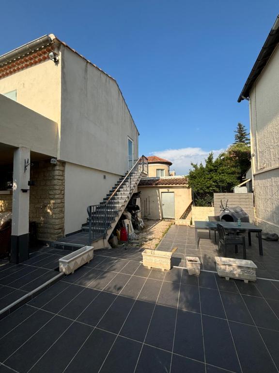 un patio avec un escalier, une table et un bâtiment dans l'établissement Villa entière pour famille, à Aramon
