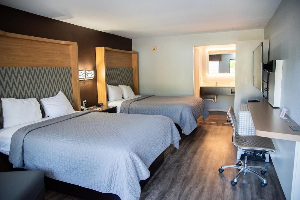 a hotel room with two beds and a desk at Columbus Inn and Suites in Columbus