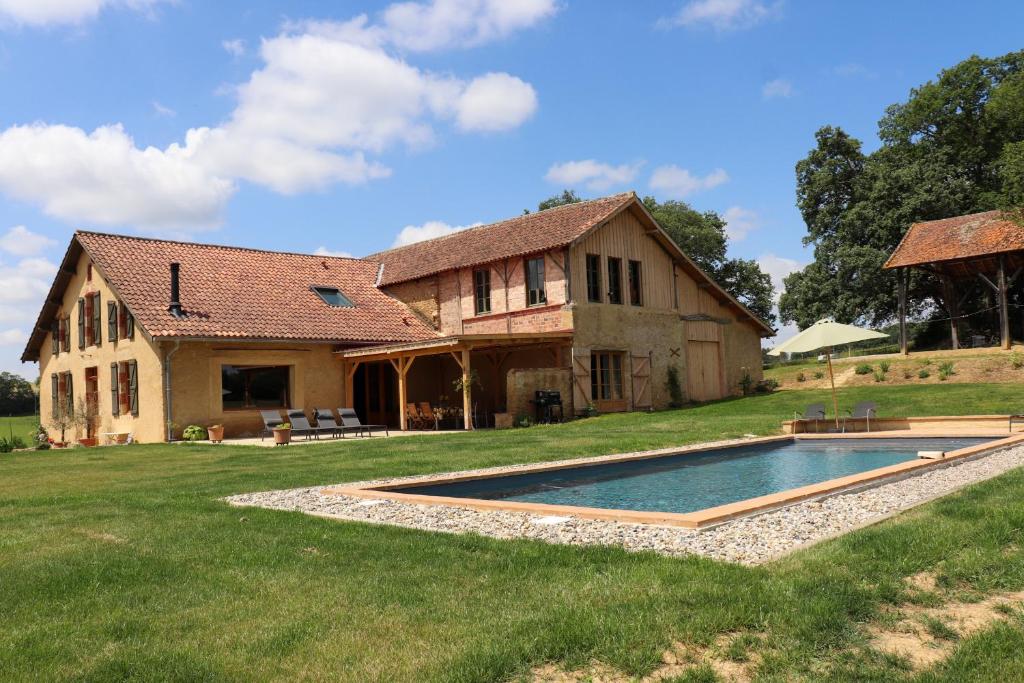 une vieille maison avec une piscine en face de celle-ci dans l'établissement Chambres d hôtes Puchouaou Nuage sur le chemin de Saint Jacques de compostelle, à Montesquiou