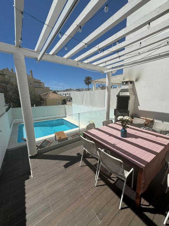 a patio with a table and chairs and a pool at Sand, Water & Sun House in Vila Nova De Cacela