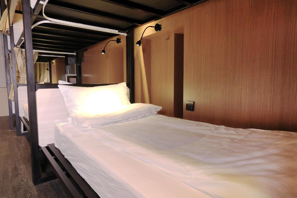 a bunk bed with white sheets and pillows on it at Angels Hostel Taipei Ximen in Taipei