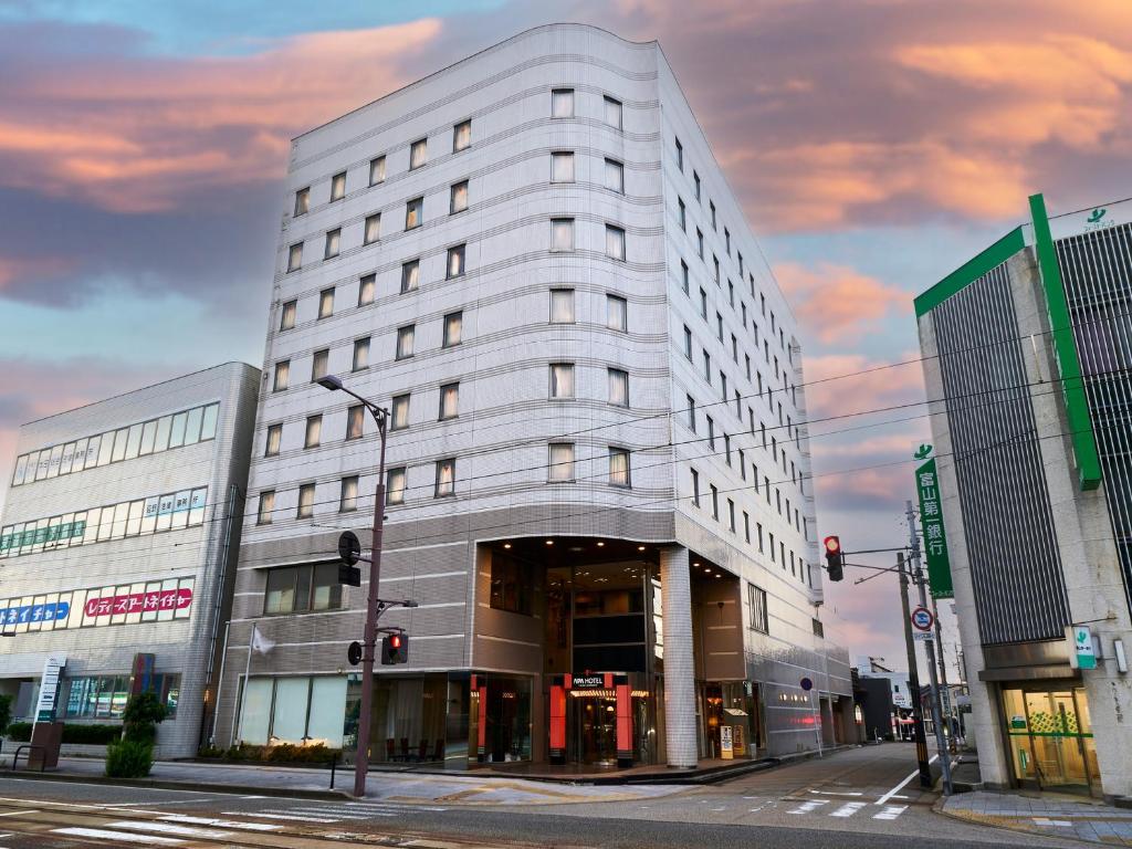Un edificio alto y blanco en una calle de la ciudad. en APA Hotel Takaoka Marunouchi, en Takaoka