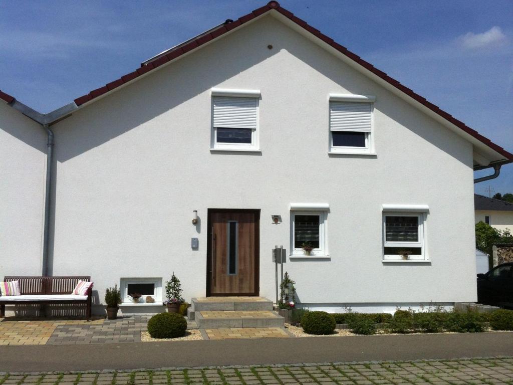 una casa bianca con una panchina davanti di Ferienwohnung Heike a Dettingen an der Erms