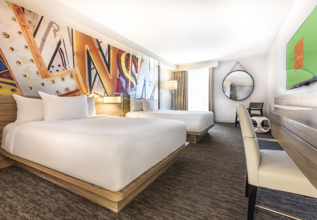 a hotel room with two beds and a mirror at The LINQ Hotel and Casino in Las Vegas