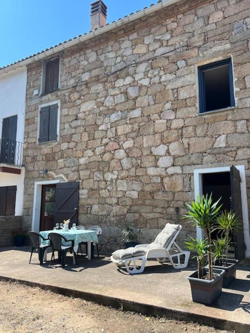 un patio avec une table et des chaises et un bâtiment dans l'établissement Charmante maison à louer, à Bastelicaccia