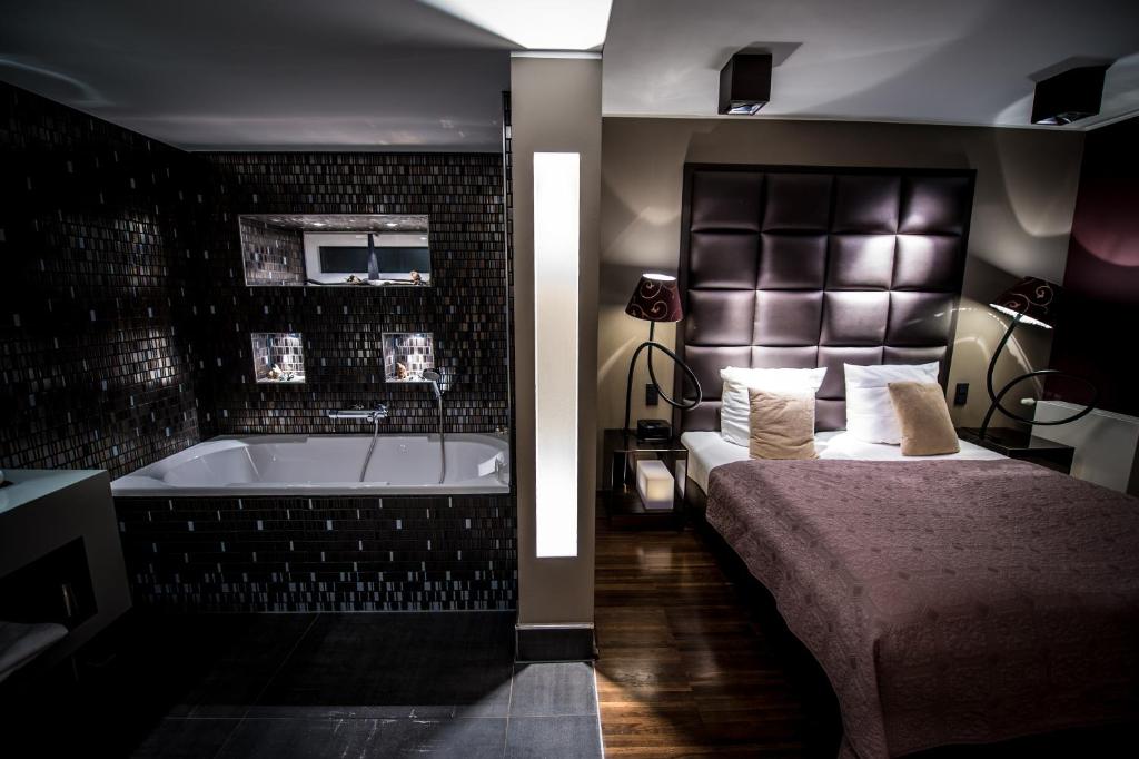a bedroom with a bed and a bath tub at Hotel Rosenmeer in Mönchengladbach