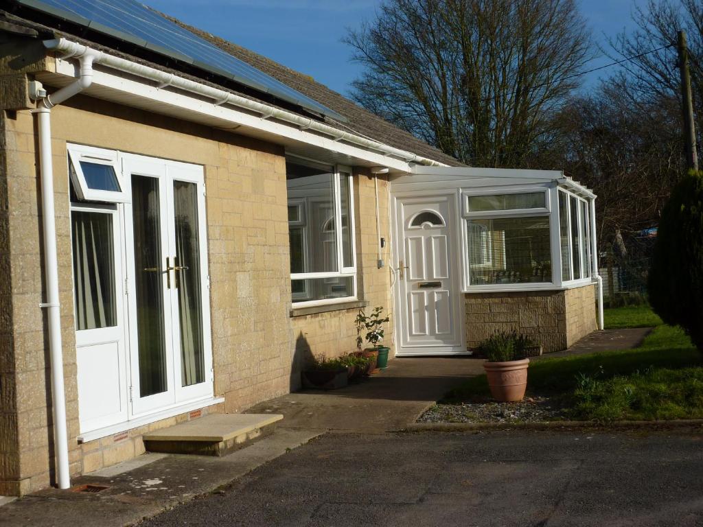 Casa de ladrillo con puerta blanca y ventanas en Snipelands Bed and Breakfast., en Flax Bourton