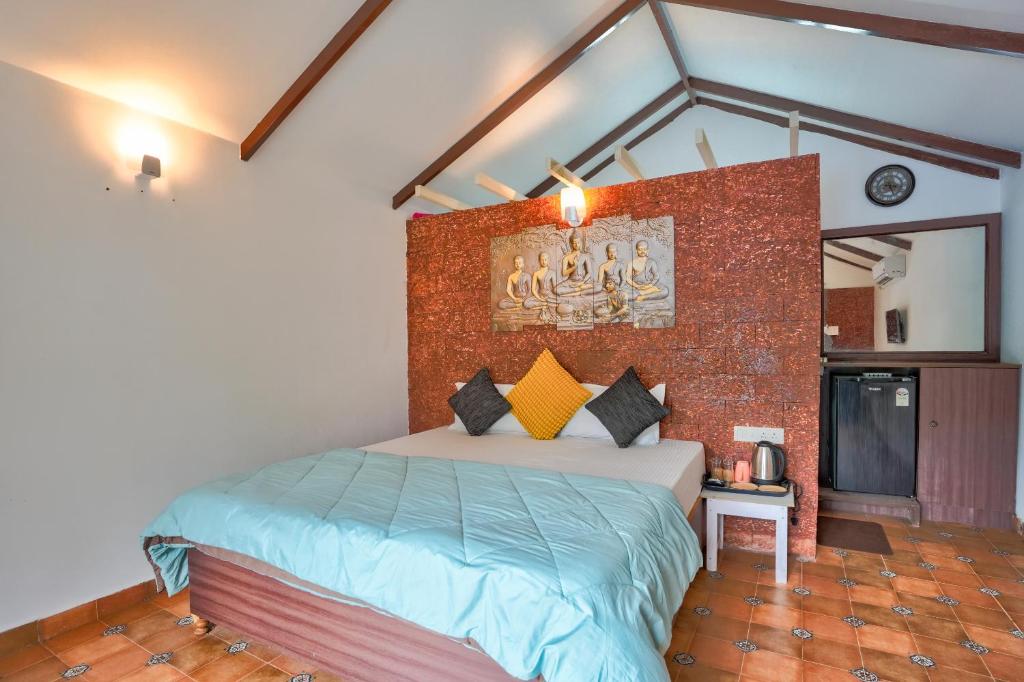 a bedroom with a bed and a brick wall at Golden Rice Resort & Cottages in Candolim