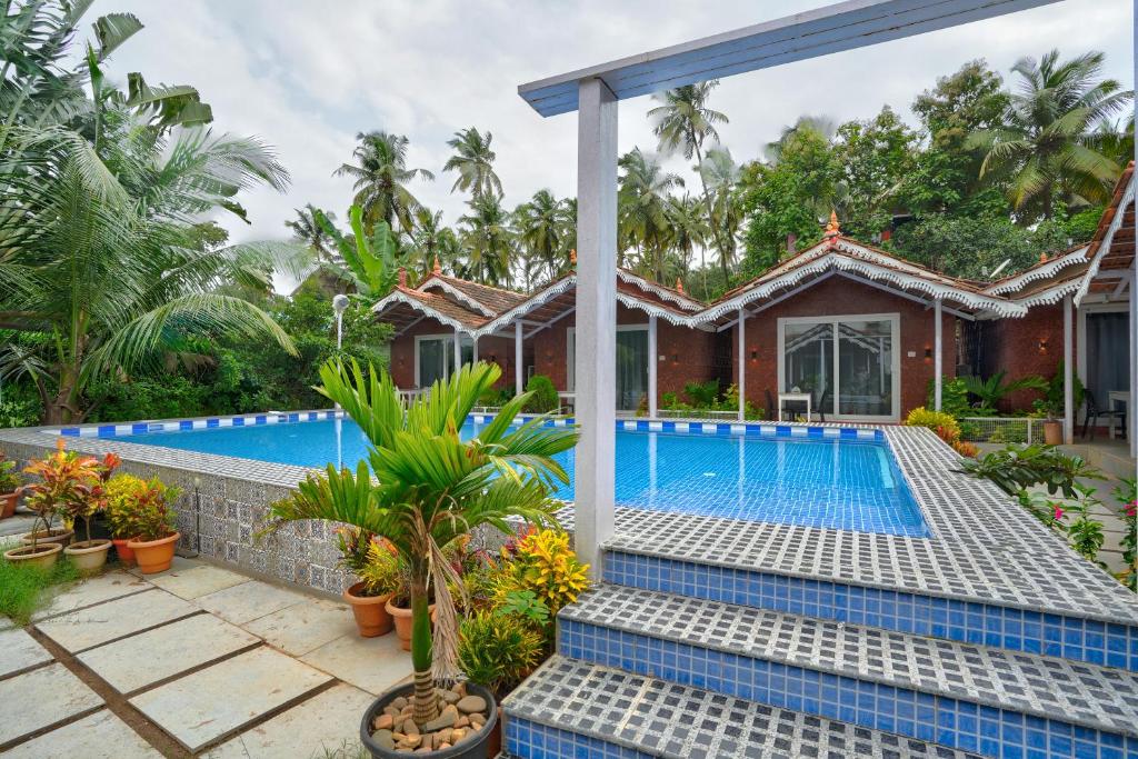 a villa with a swimming pool in a resort at Golden Rice Resort & Cottages in Candolim