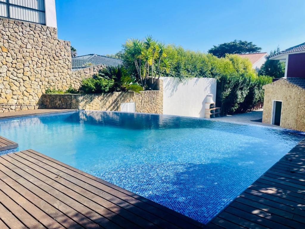 - une piscine dans une cour avec une terrasse en bois dans l'établissement GLICINIAS Cascais Villa, à Birre