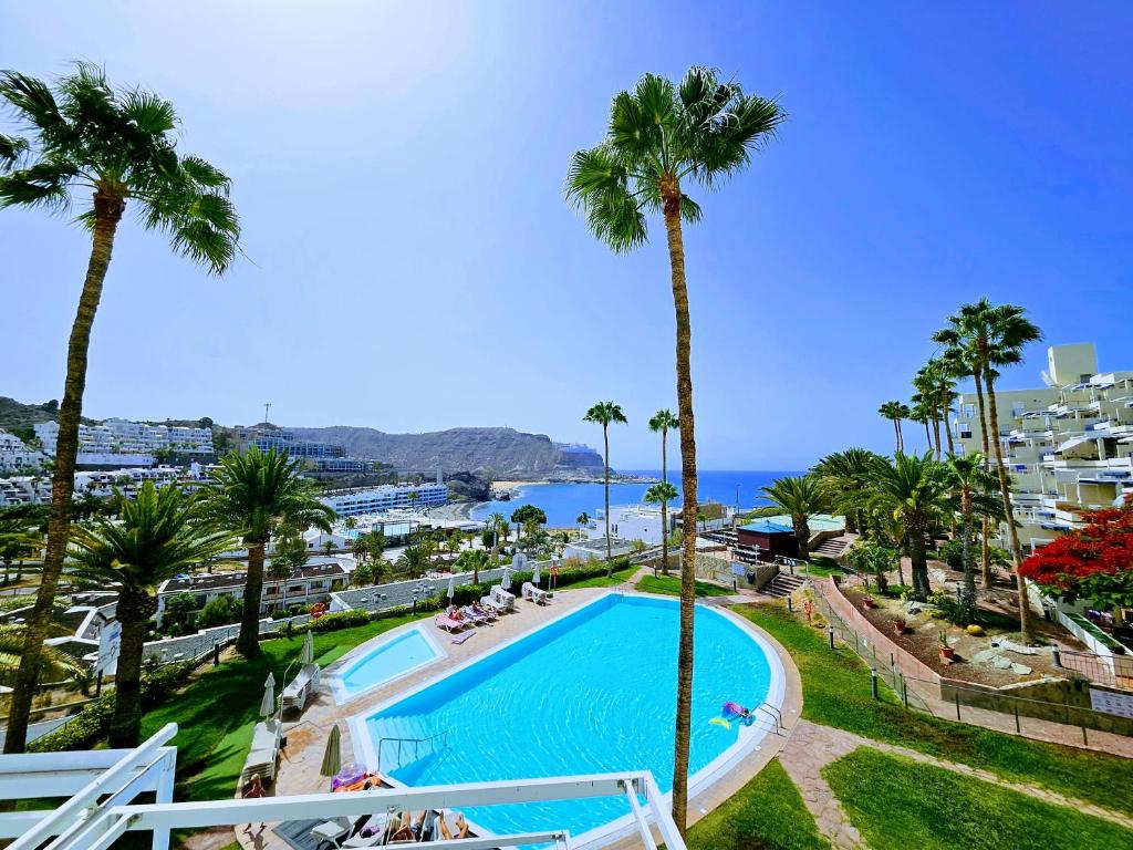 a swimming pool with palm trees and the ocean at Wonderful Ocean View in Playa del Cura