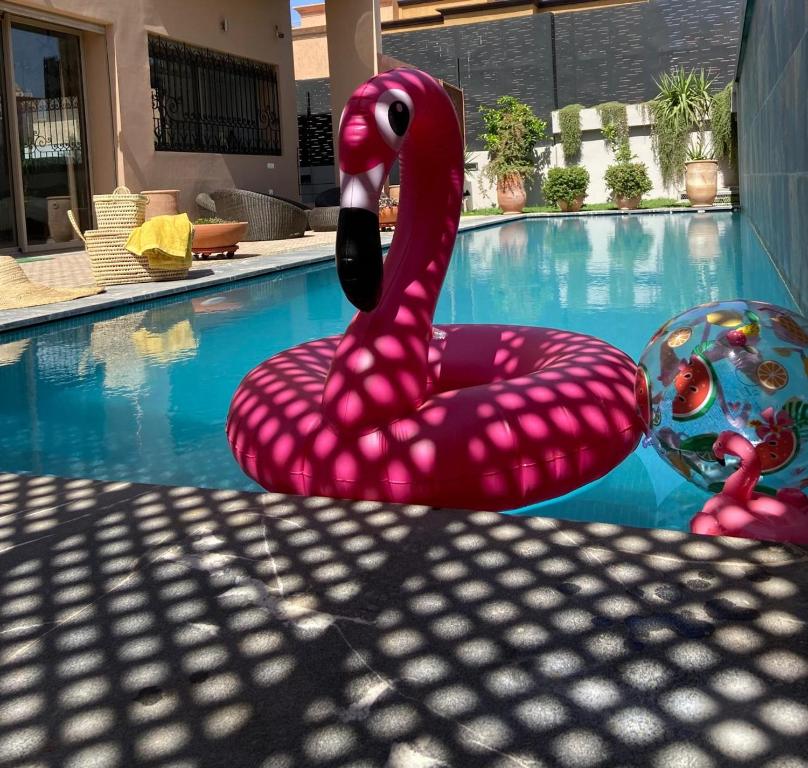 a pink swan statue sitting next to a swimming pool at VILLA De LUXE in Marrakesh