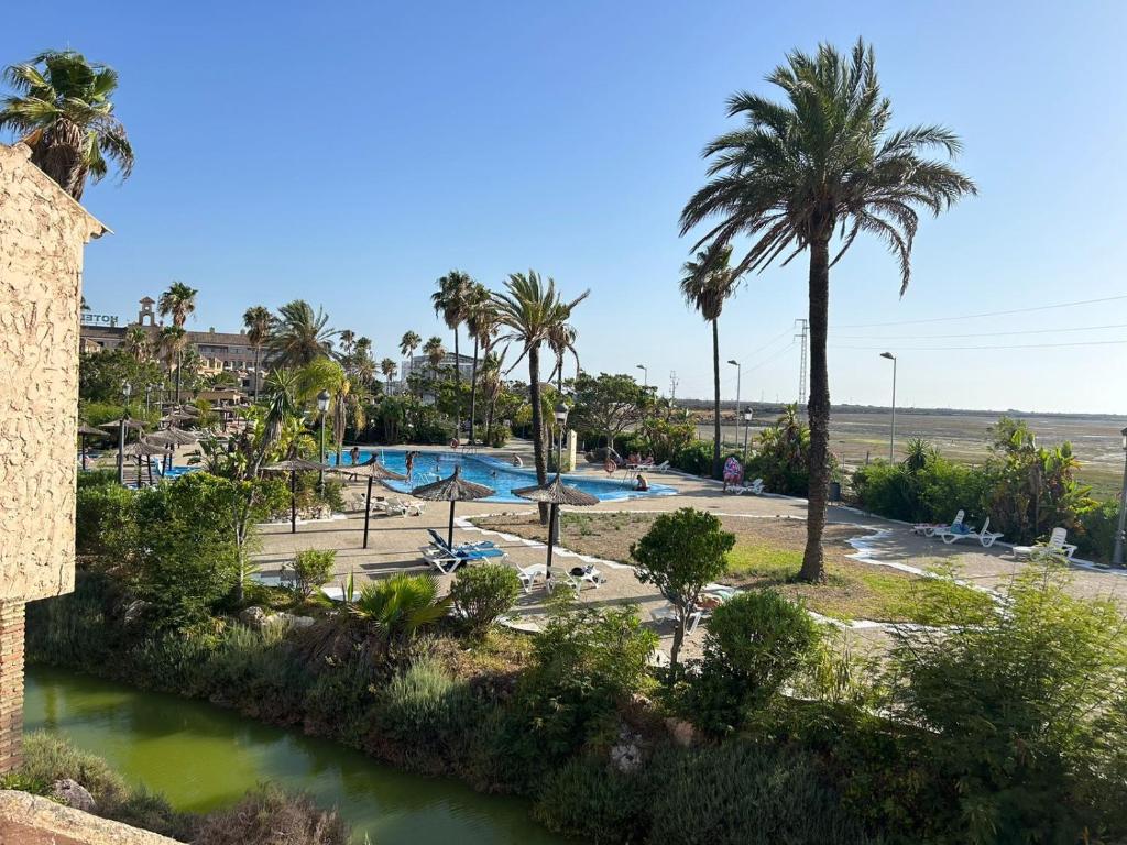a resort with a pool and palm trees at Aires de la Bahia in San Fernando
