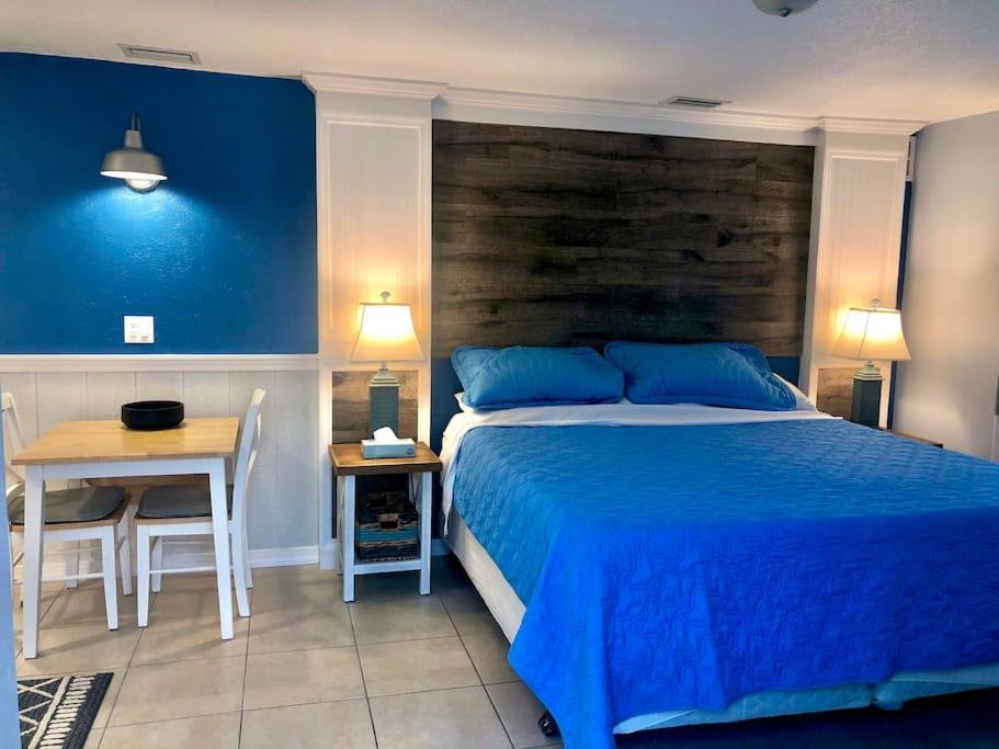 a bedroom with a blue bed and a table and chairs at Sand Dollar Studio Pool Daily Rentals in Sarasota