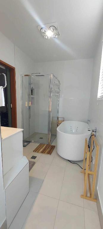 a white bathroom with a tub and a glass shower at Studio Apartment in Collingwood Park