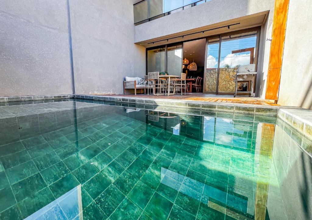einen Pool in einem Haus mit grünen Fliesen in der Unterkunft Milagres Hospedagens - Casa Praia & Capela in São Miguel dos Milagres