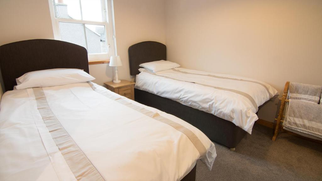 a bedroom with two beds and a window at Morris Gardens Apartments in Oldmeldrum