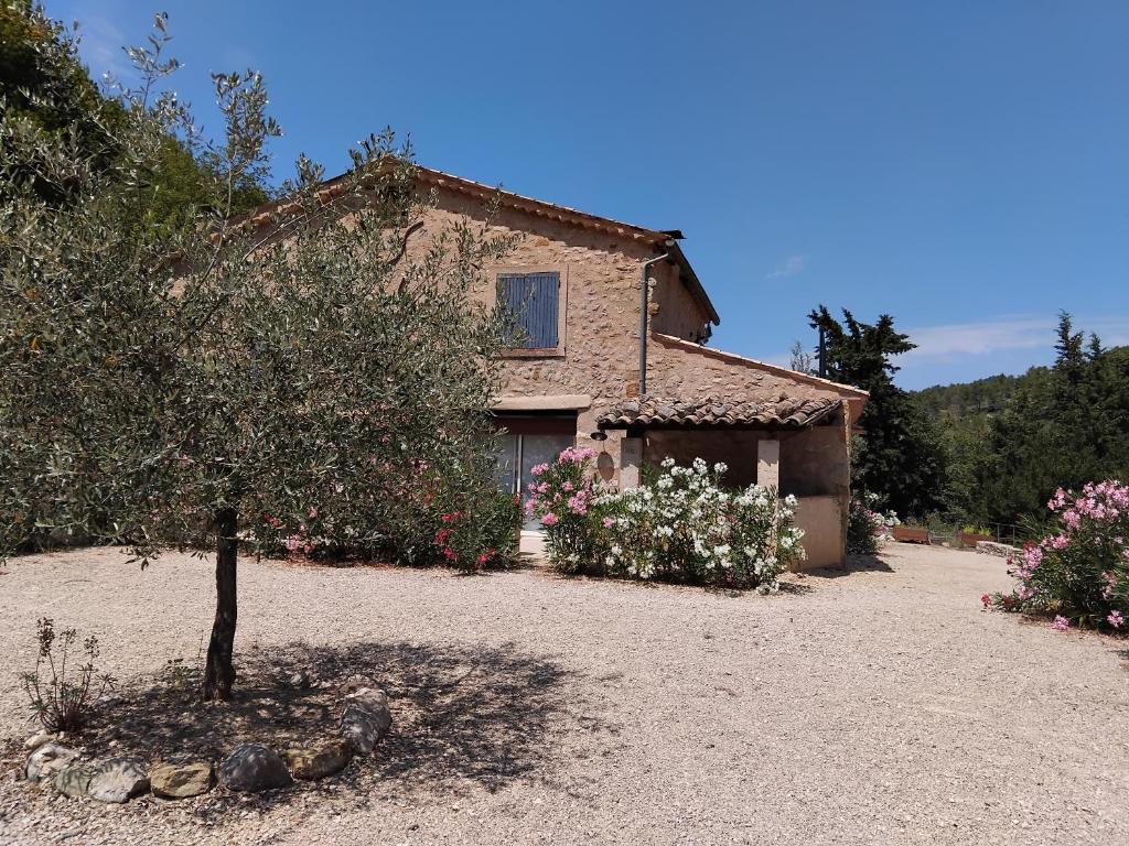 una casa con un albero e dei fiori davanti di 10 mn Buis les Baronnies a Plaisians