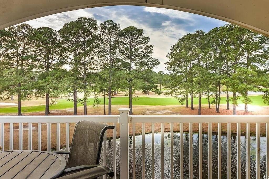einen Balkon mit Blick auf einen Golfplatz durch ein Fenster in der Unterkunft Beautiful 1500 s f 3 Bd - 2 Ba condo overlooking stream and golf course in Myrtle Beach