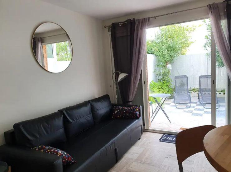 - un salon avec un canapé en cuir noir et un miroir dans l'établissement studio Pointe Croisette avec terrasse, à Cannes