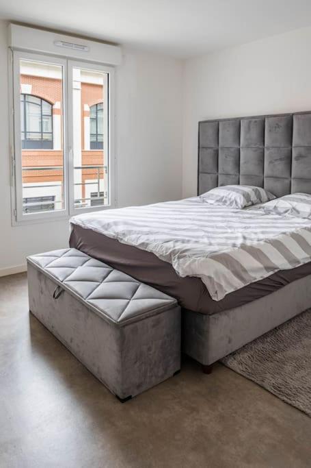 un lit dans une chambre avec une grande fenêtre dans l'établissement L'escapade confortable, au Blanc-Mesnil