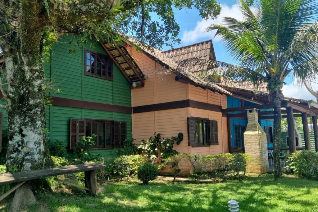 una casa verde con una palma di fronte di Chalé Carvalho - Salmão a Itapoa