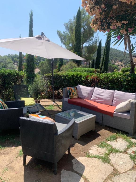 une terrasse avec un canapé, un parasol et des chaises dans l'établissement CAP Estérel FH007 , PISCINE CHAUFFÉE DU 05 avril au 02 Novembre , superbe parc aquatique ,Animations restaurants,boutiques, activités sportives village Club tout inclus, à Saint-Raphaël