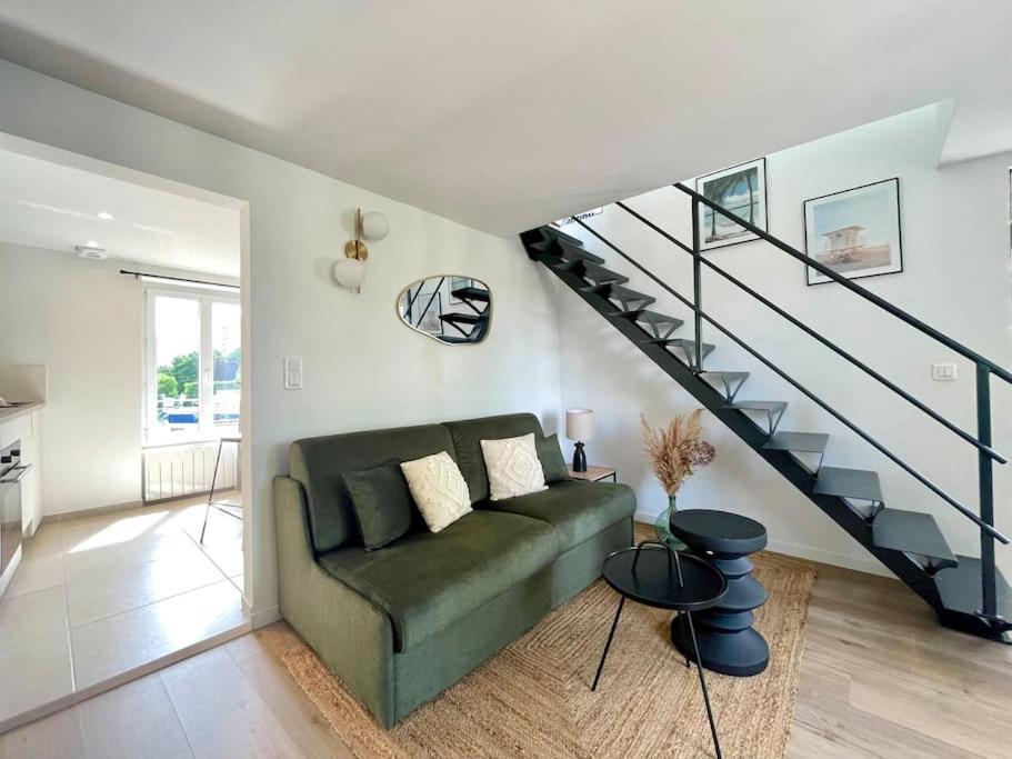 a living room with a green couch and a staircase at Duplex rénové secteur Lac d'Enghien in Saint-Gratien