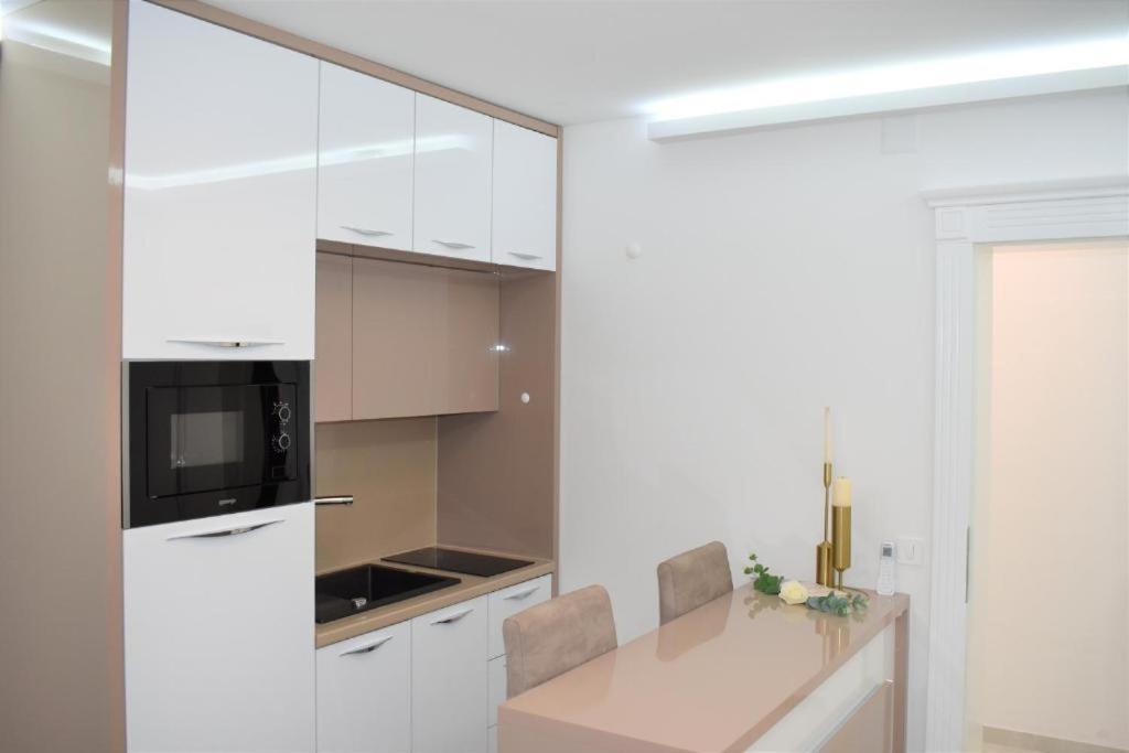 a kitchen with white cabinets and a table with chairs at Moco - Novalja in Novalja