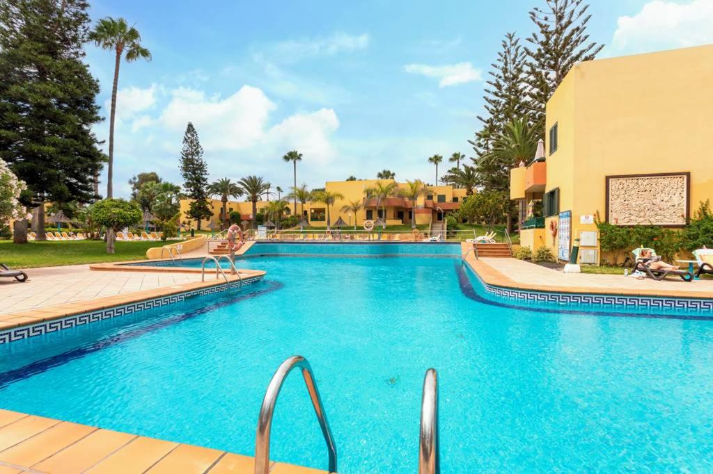 a swimming pool at a resort with blue water at Corralejo Atlantic Garden Andrew apartments Pool air conditioning in Corralejo