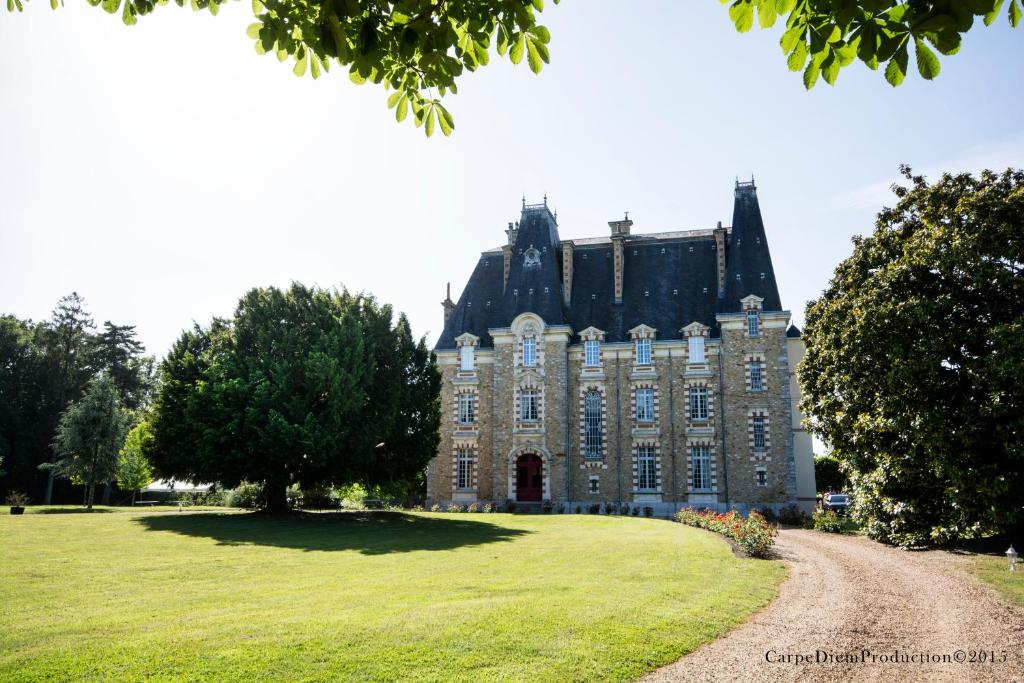 un gran castillo con un campo de hierba delante de él en Au Chateau de Montbraye, en Parigné-lʼÉvêque