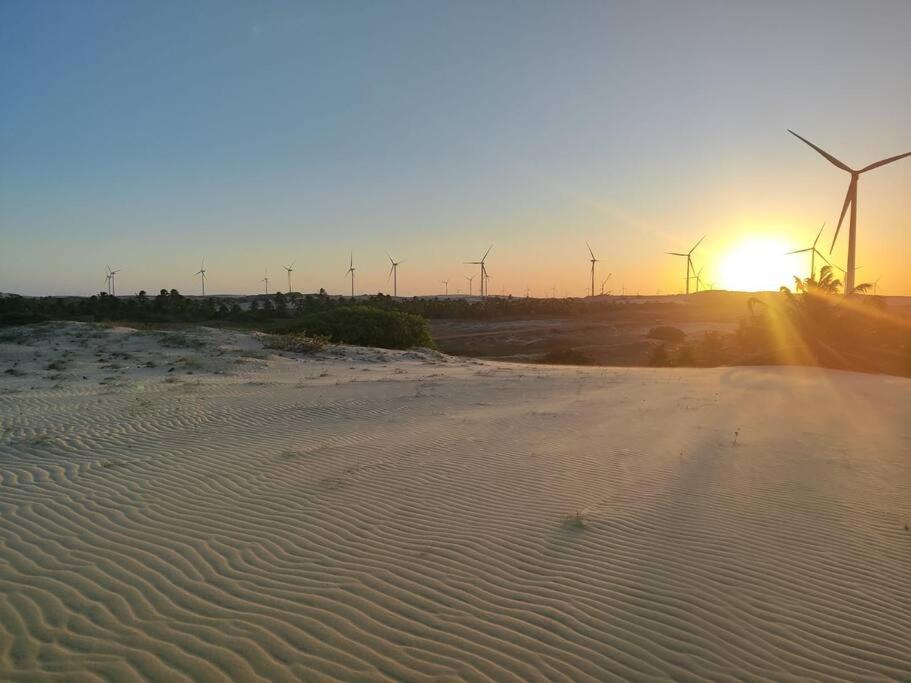 a beach with windmills in the background with the sunset at Casa Éden in Guajiru