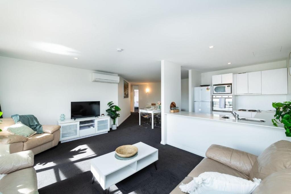 Una sala de estar con un sofá y una cocina. en Griffin Apartments Kingston ACT, en Canberra